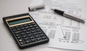 a calculator, financing paperwork, and pen on a table