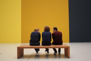 3 people sitting on a bench in a museum