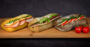 3 sandwiches on a wooden platter