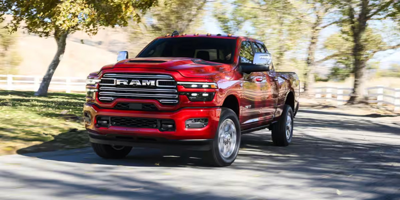 Red RAM pickup truck driving on a tree-lined road
