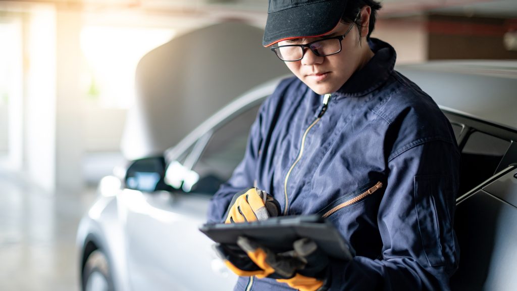 Auto technician inspecting a vehicle with a digital tablet during service
