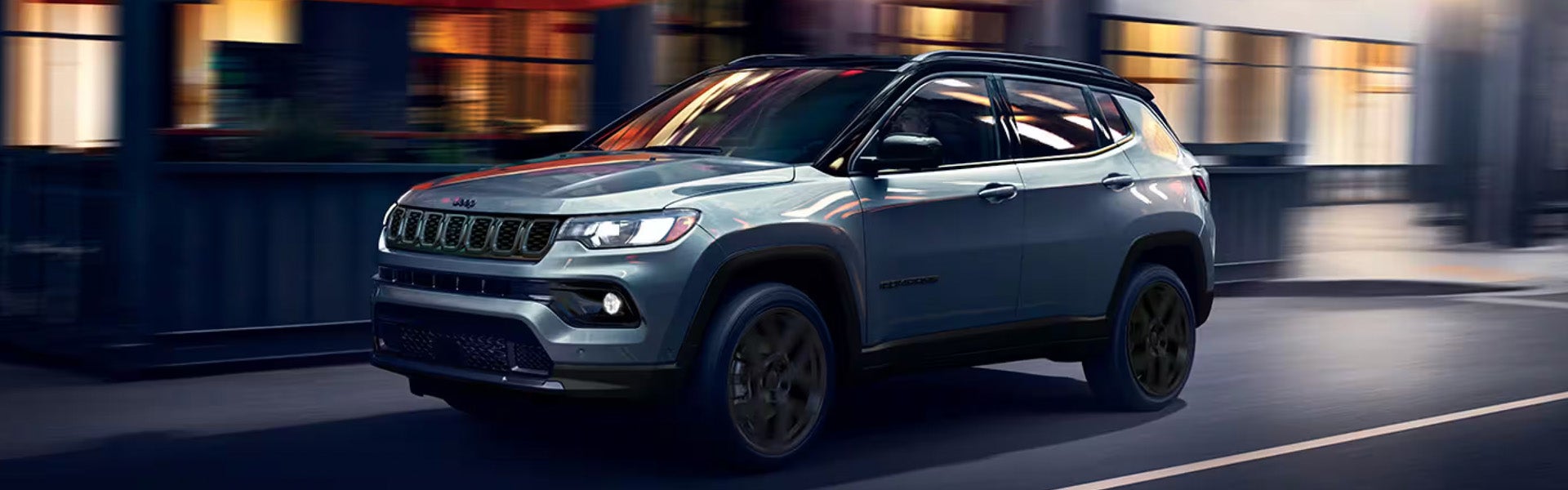 Gray Jeep Compass SUV driving through a city street.
