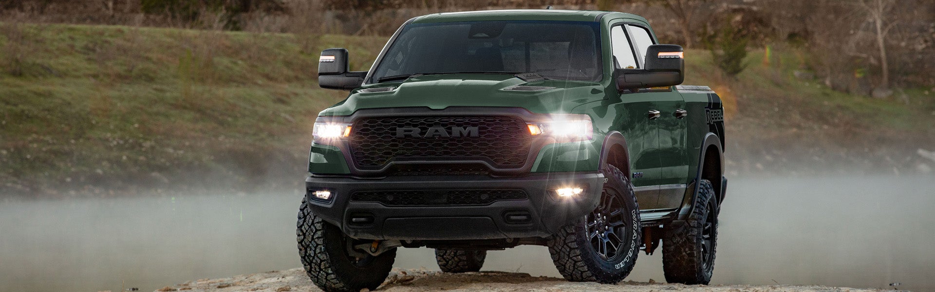 Green RAM pickup truck parked outdoors on a rocky landscape.