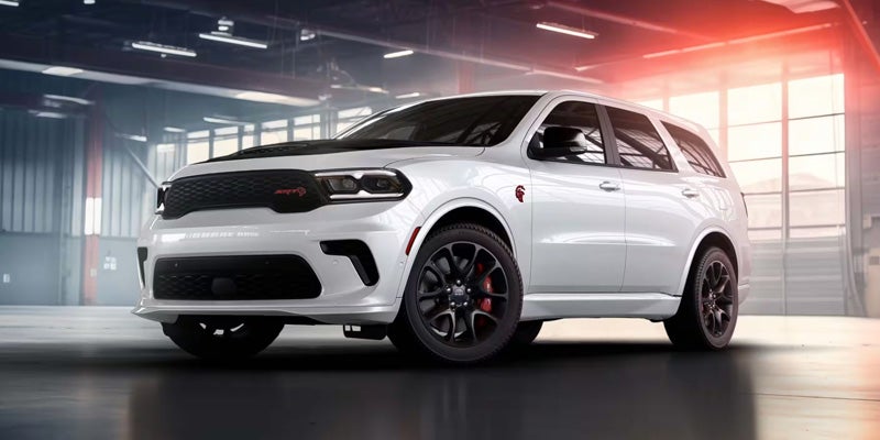 White Dodge Durango SRT performance SUV displayed in a modern showroom with sporty black wheels.